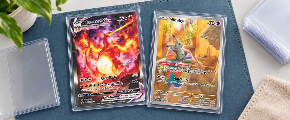 Charizard- och Mimikyu-kort i skydd på ett blått samlarunderlägg